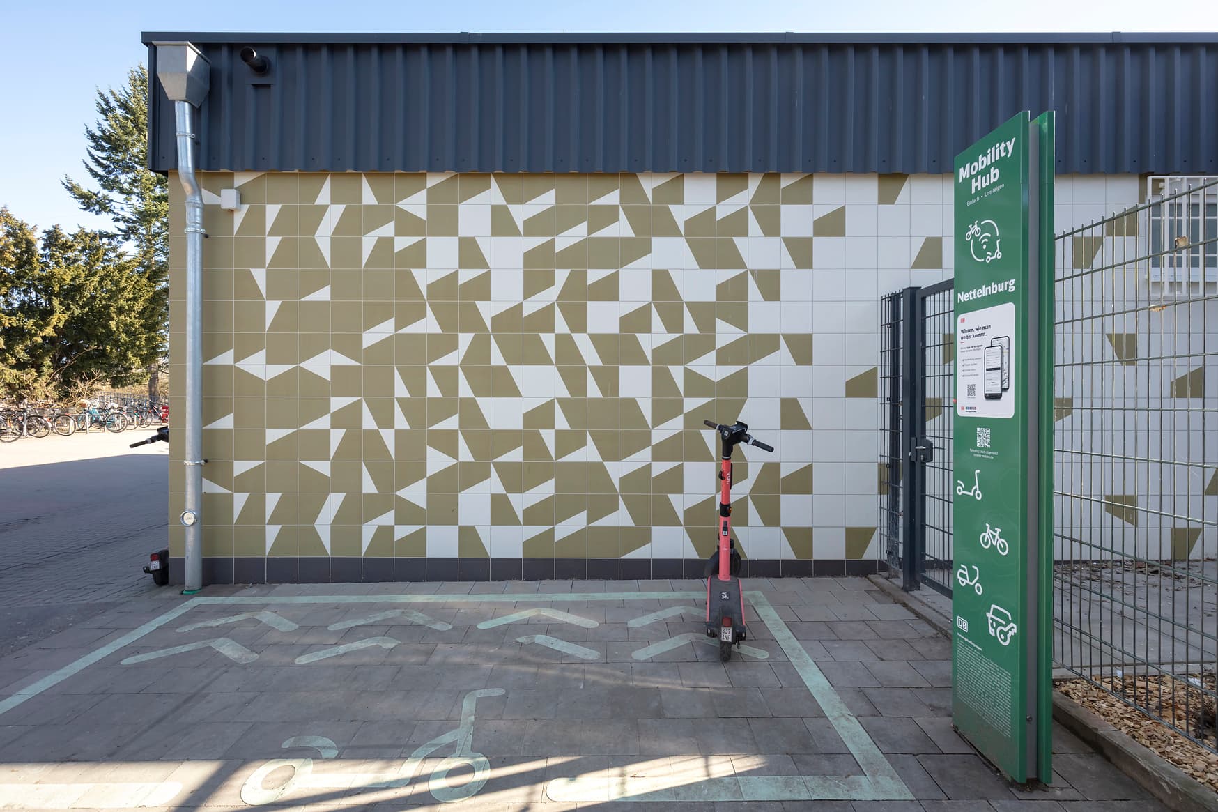 Ein gekennzeichneter Bereich für E-Scooter vor einer grün-weiß geflieesten Wand
