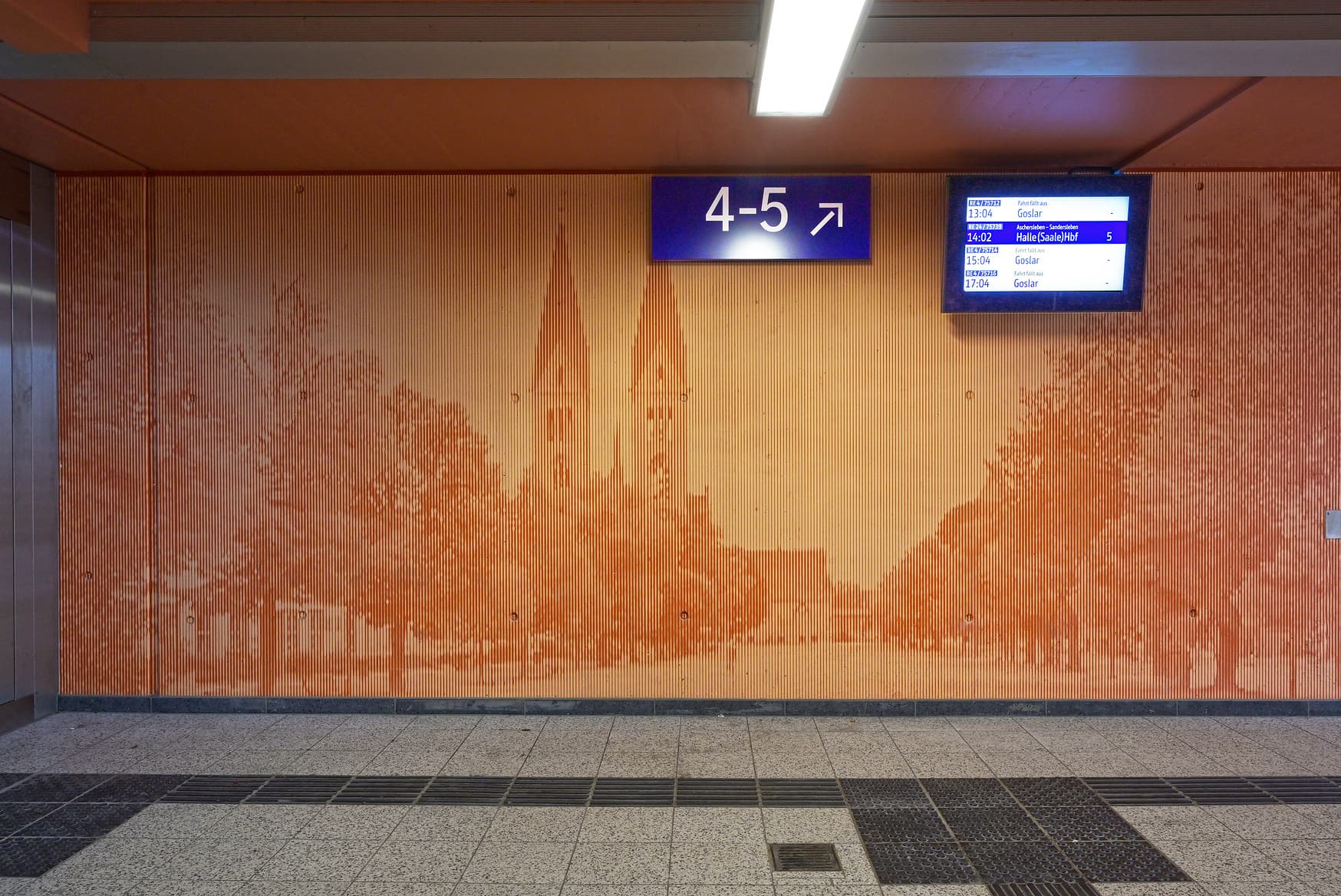 Personenunterführung mit blauem Wegweiser und Informationsmonitor.