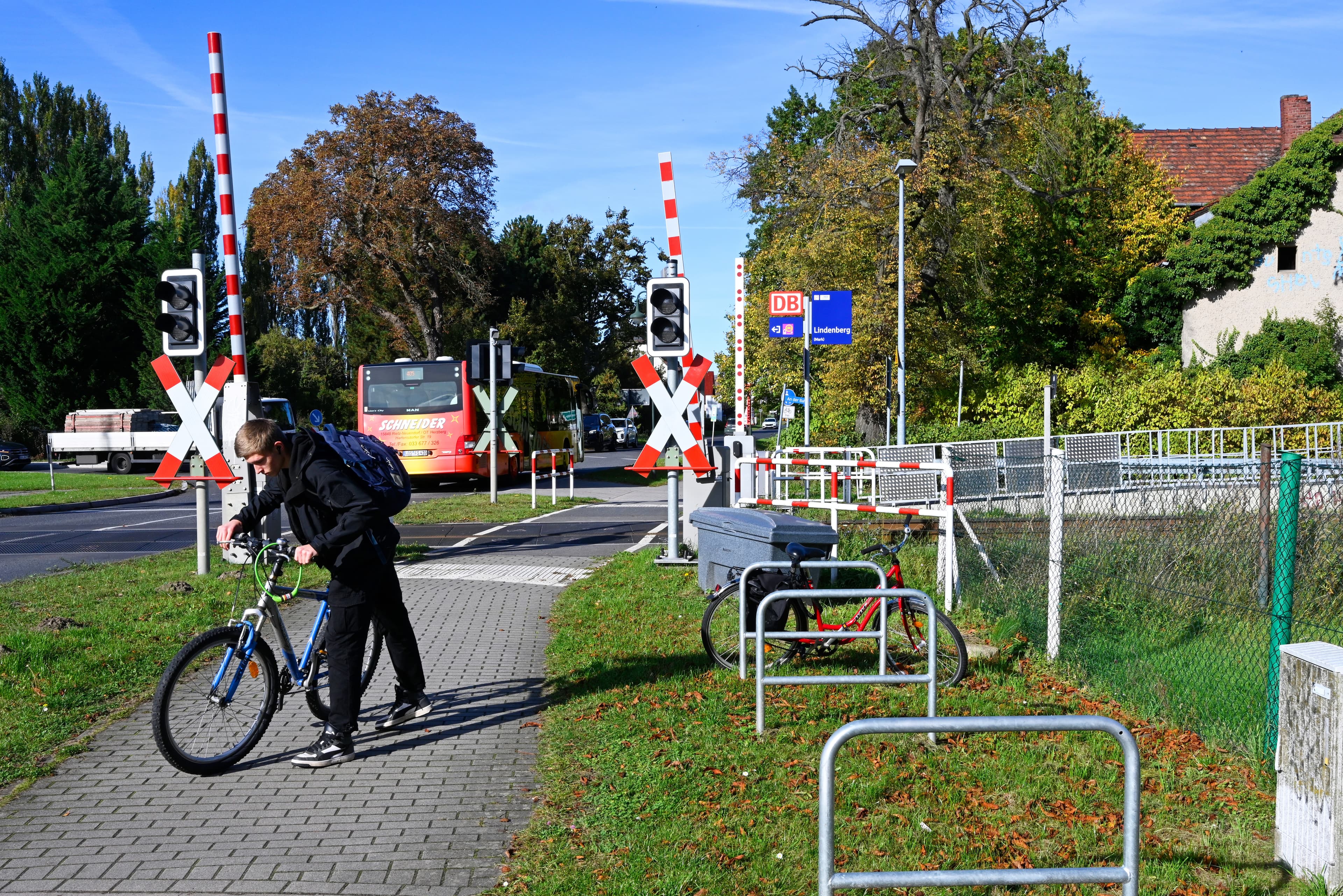 Ein Fahrradfahrer vor einem Bahnübergang neben Fahrradbügeln.