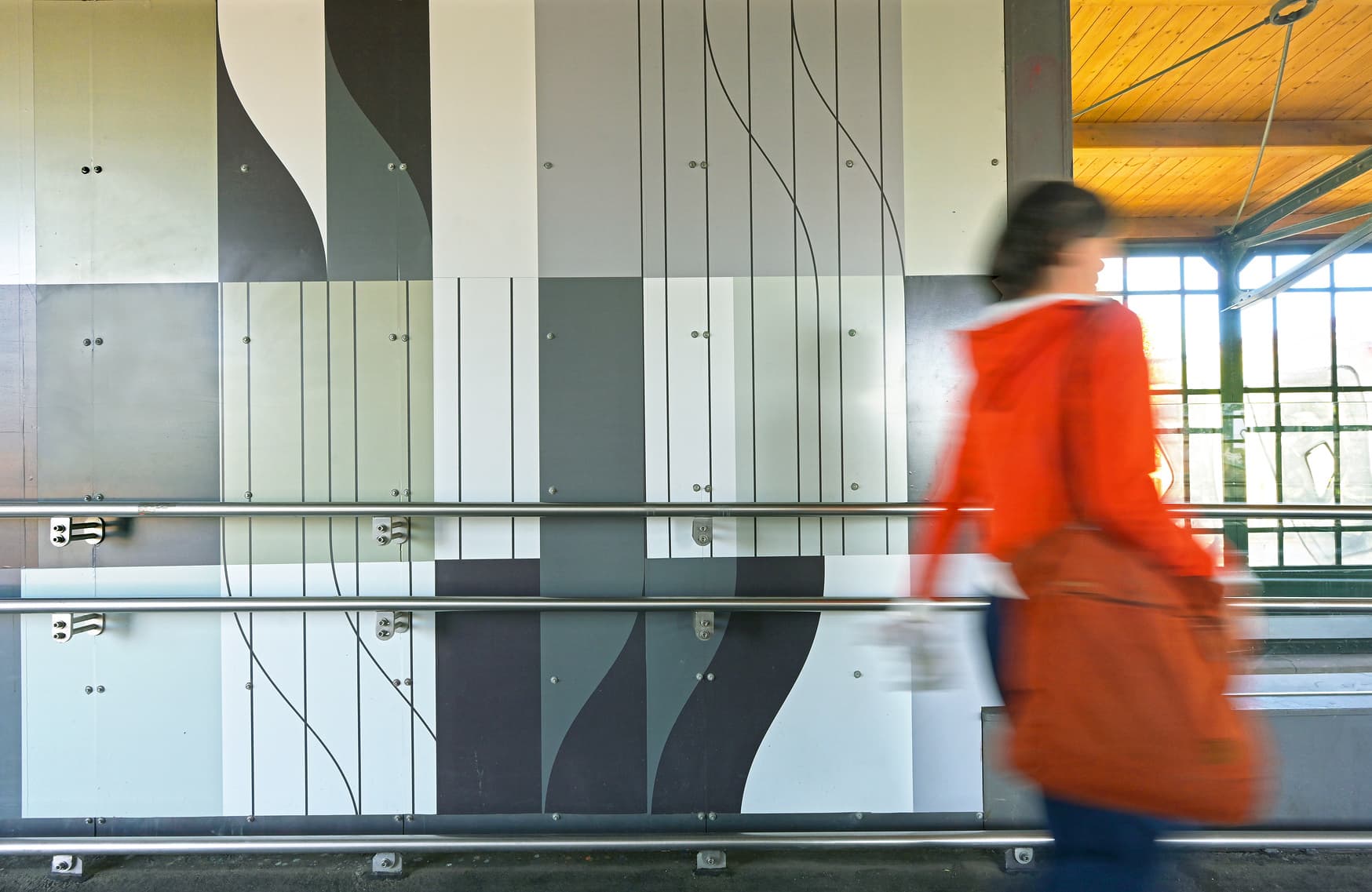 Systemgrafik auf einer Wand am Bahnsteig mit einem Handlauf.