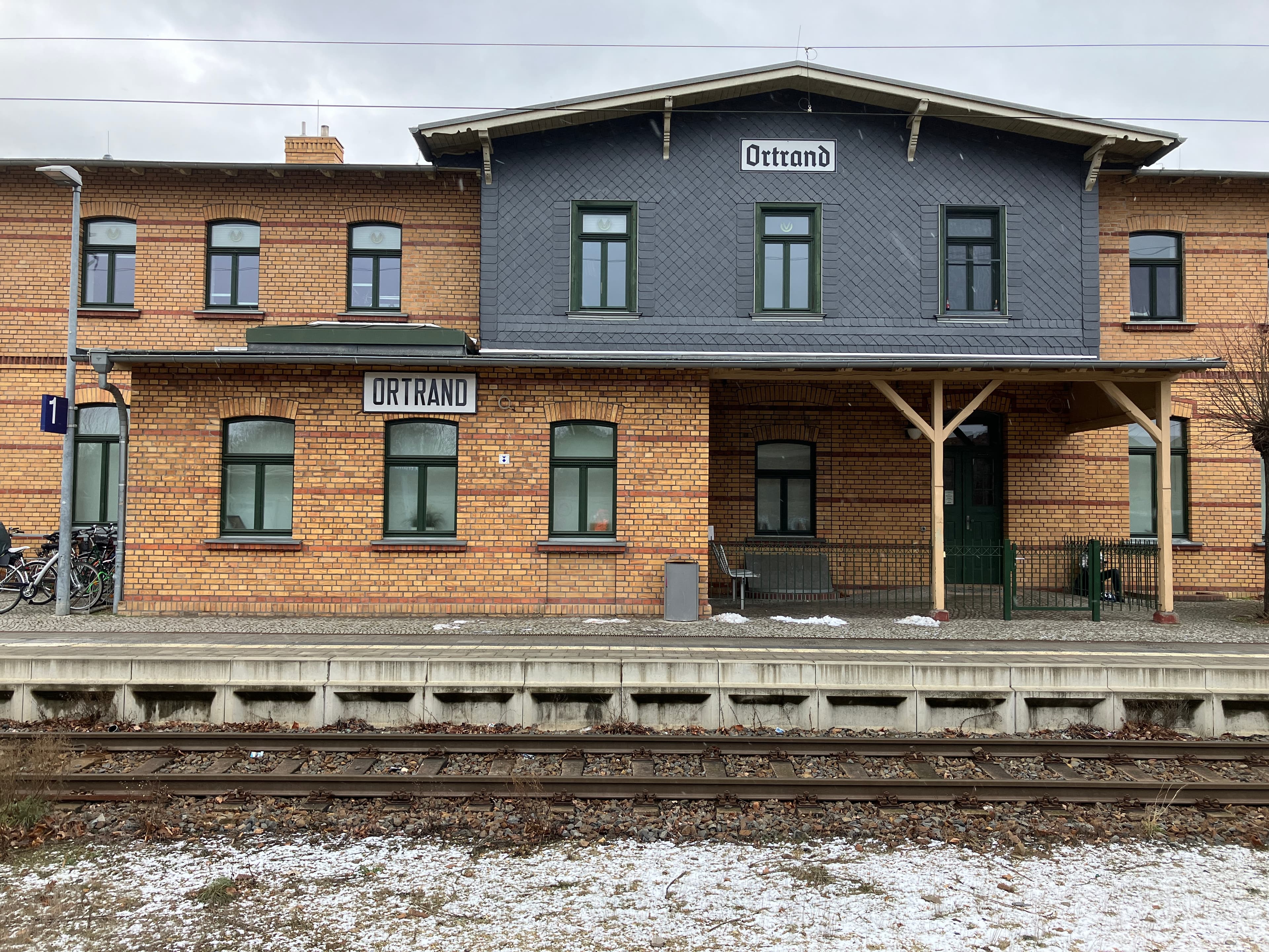 Ein Bahnhofsgebäude vor Gleisen.