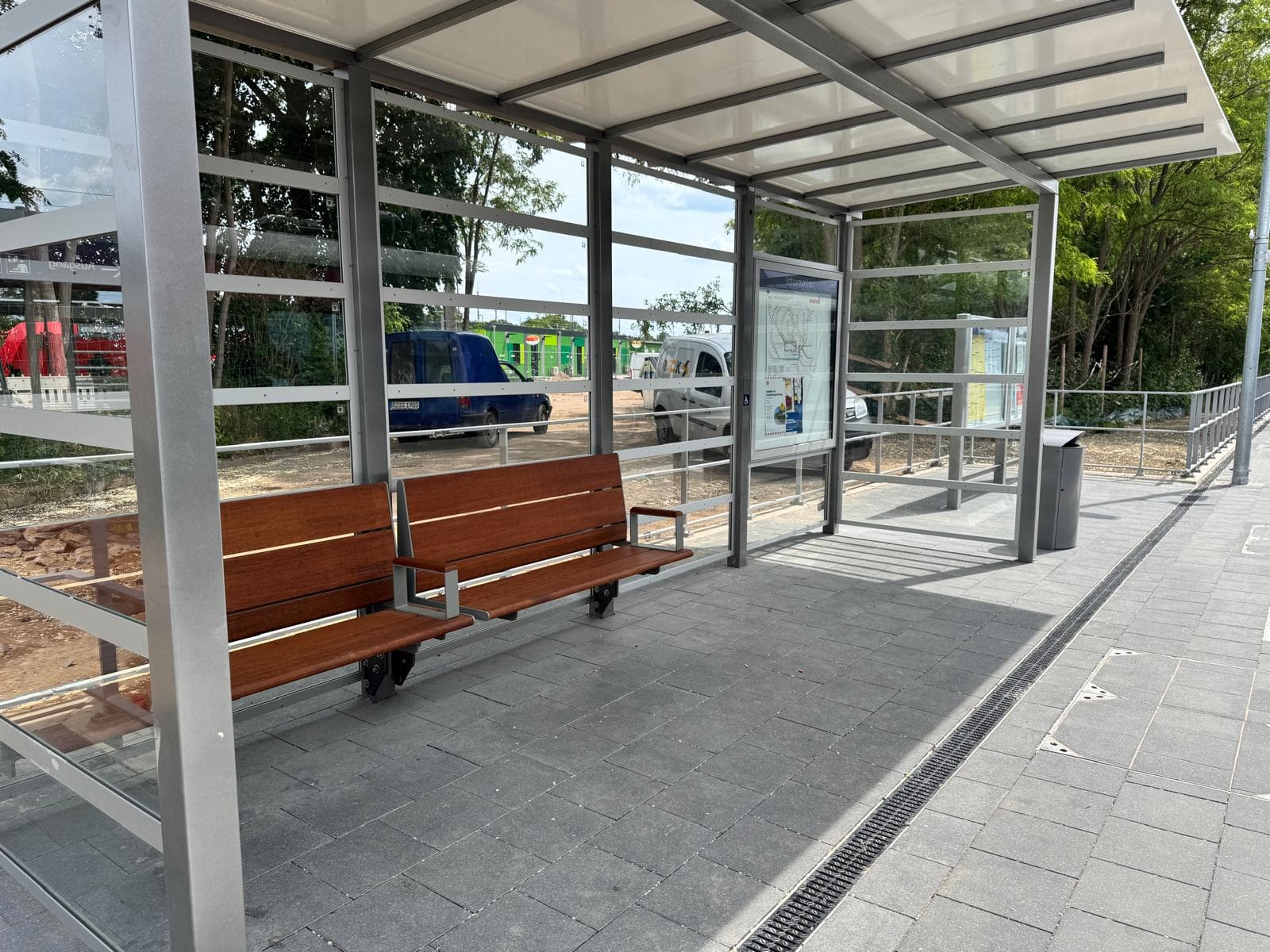 Vollverglaster Wetterschutz mit Bank und Vitrine.