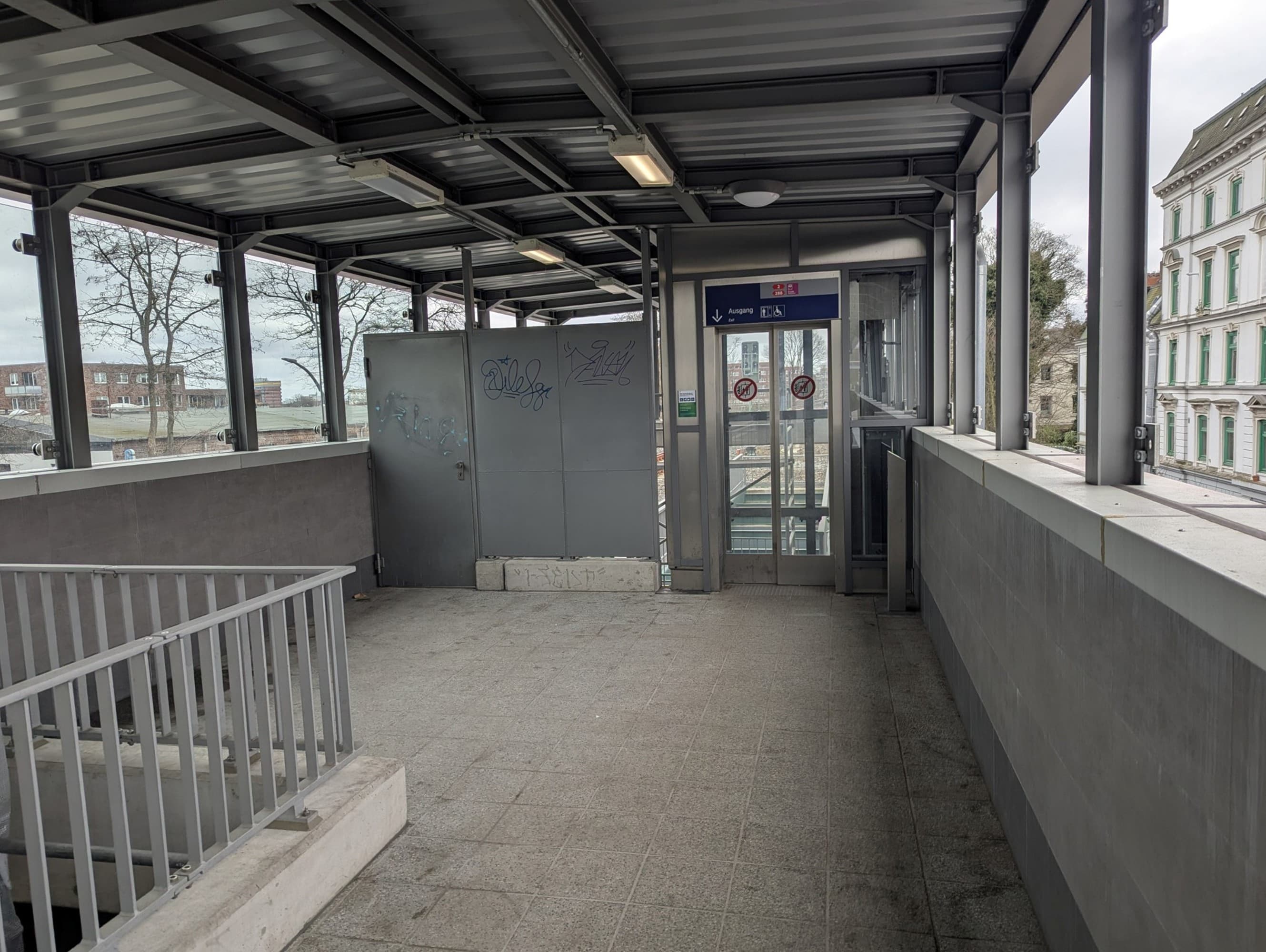 Der Zugangsbereich zum Aufzug, Geländer, Boden, Wand, Decke und Türen neben dem Aufzug sind in Grautönen. Der Aufzug selbst ebenfalls mit grauen Türrahmen.