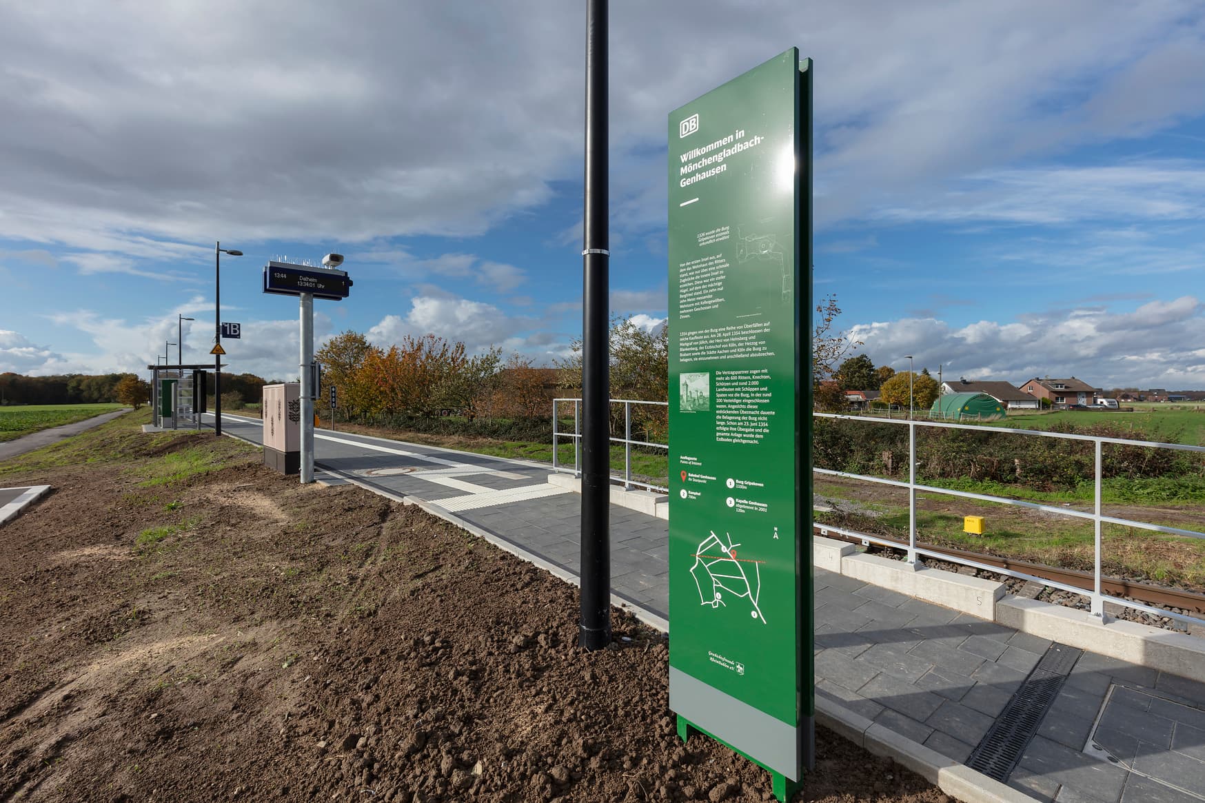 Eine grüne Informationstafel neben der Rampe zum Bahnsteig,