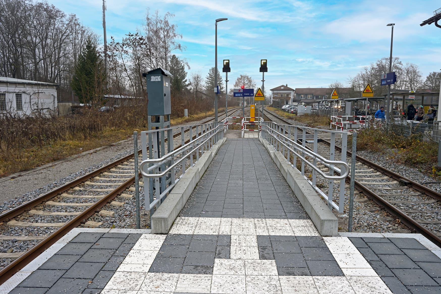 Die Rampe mit Handlauf an beiden Seiten zu einem Bahnsteig. Links und rechts davon liegen die Gleise. 