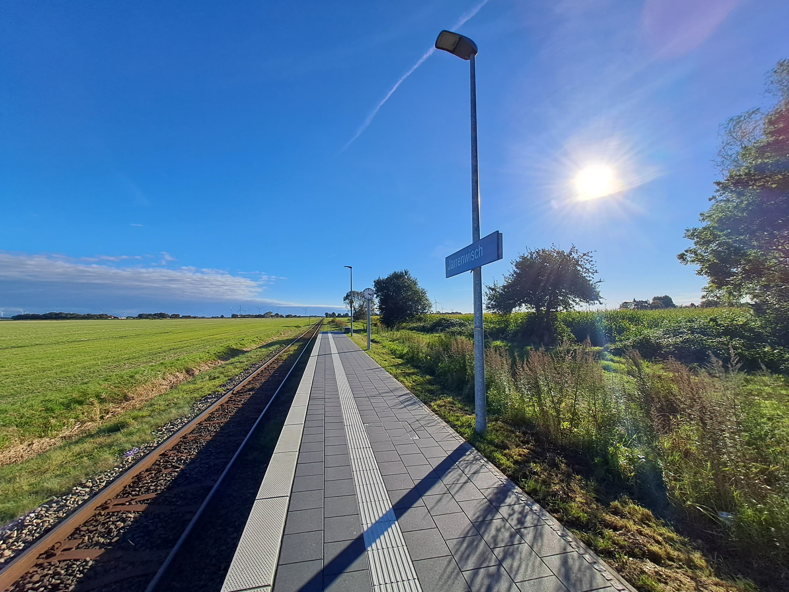 Die Marschlandschaft mit Bahnsteig und Bahnsteigsuhr.