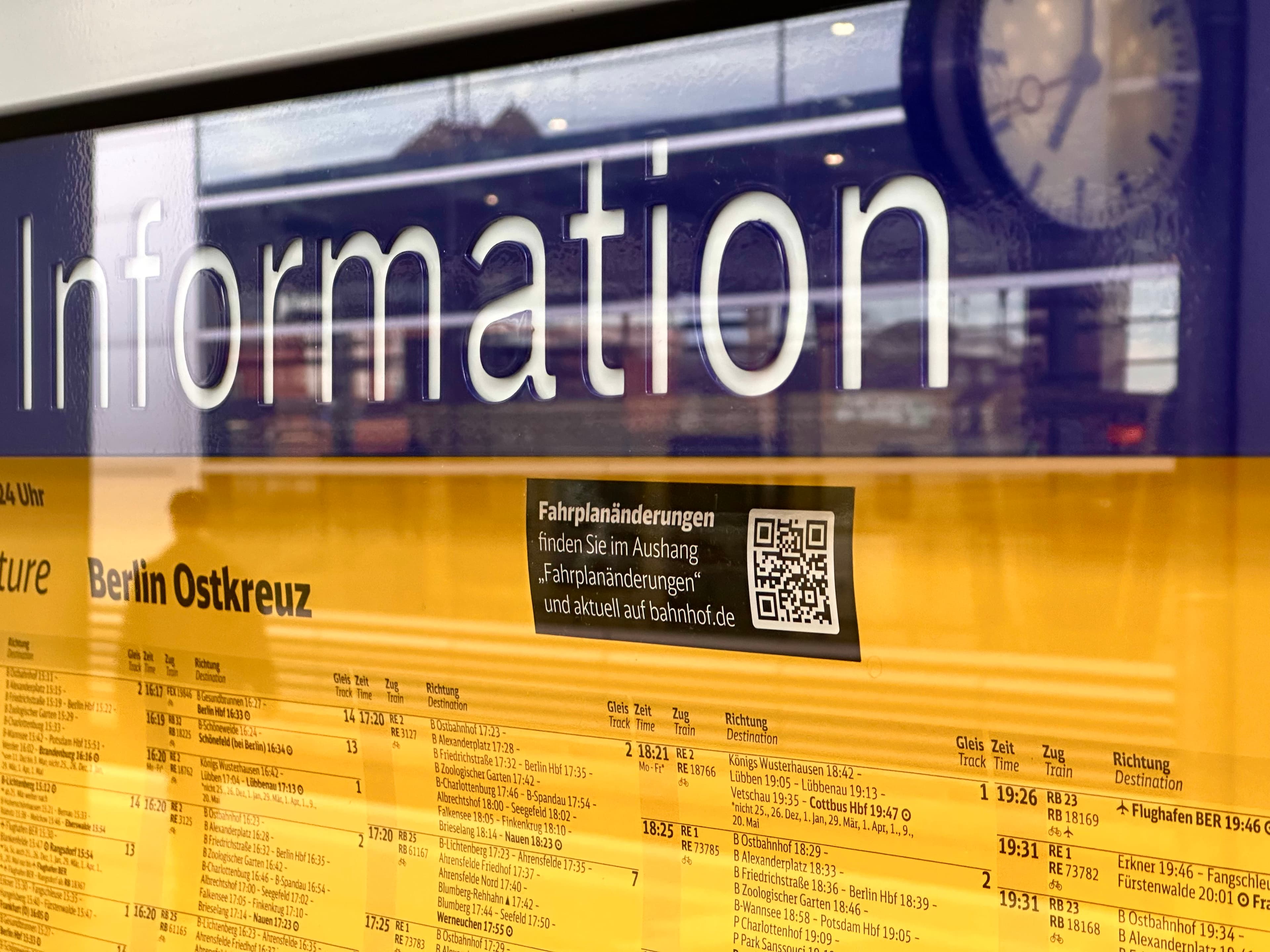 A yellow paper timetable for Berlin Ostkreuz with a printed QR code.