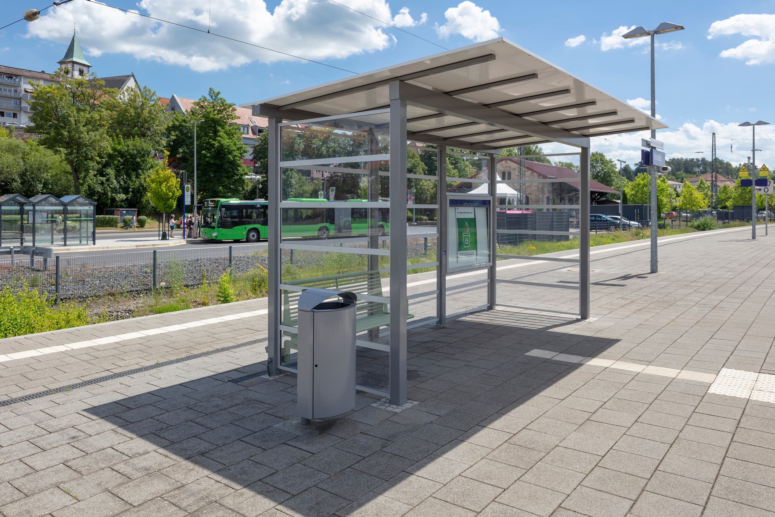 Sanierter Bahnsteig mit einem neuen Wetterschutzhaus mit Calidum Sitzbank, neuer Vitrine, neuer Beschilderung und neuem Mülleimer am Bahnhof Hünfeld.
