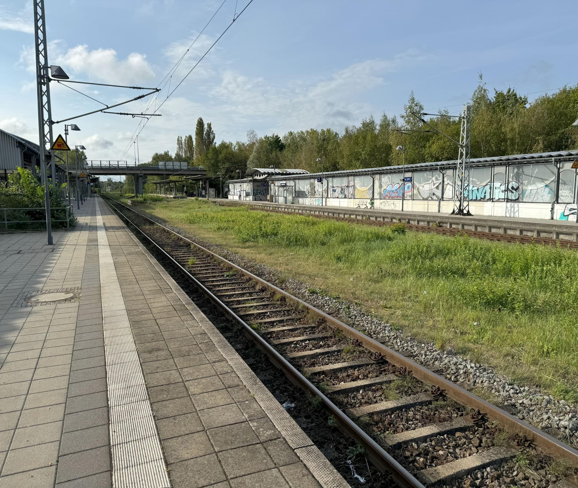Blick von Bahnsteig 1 über die Gleise auf Bahnsteig 2. Die Scheiben an der Rampe sind völlig von Graffiti überzogen.
