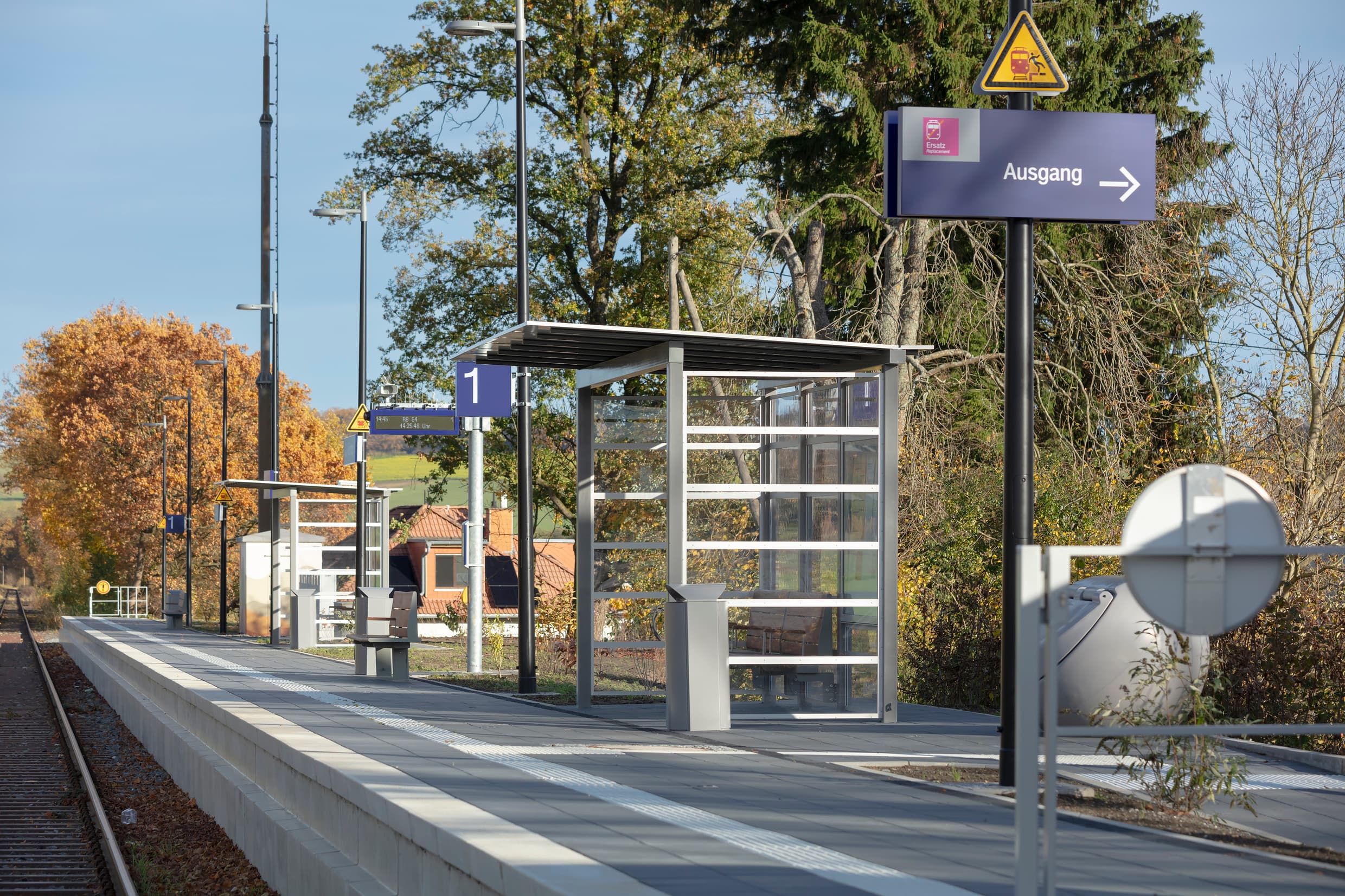 Der Bahnsteig in voller Länge mit Beschilderungen und zwei Wetterschutzhäuschen.