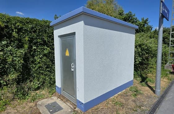 Blassblau angestrichenes Trafo-Haus mit dunkelblauen Farbakzenten oben und unten.