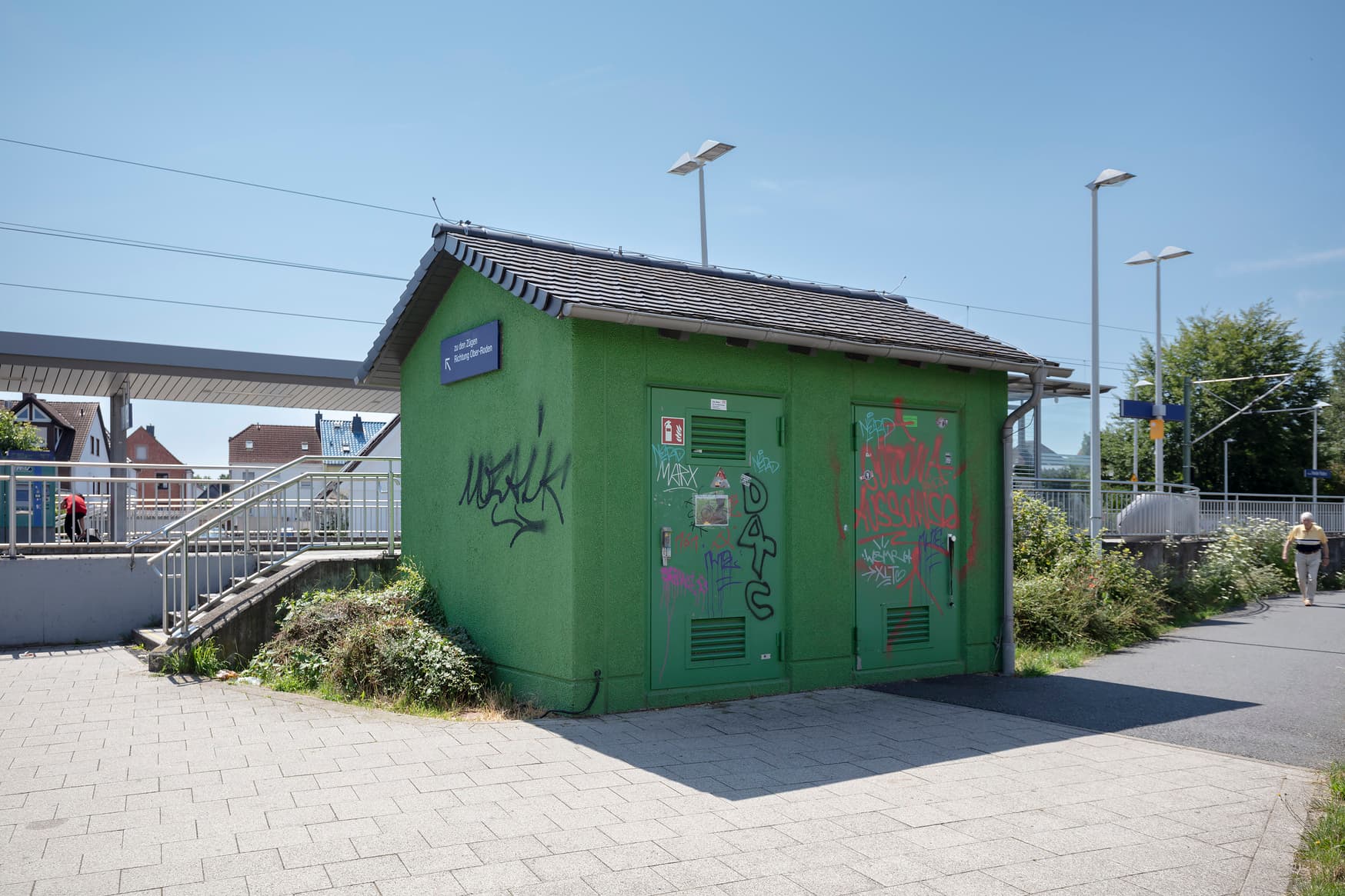 Ein grün gestrichenes Stromhaus mit Graffiti an allen Seiten.