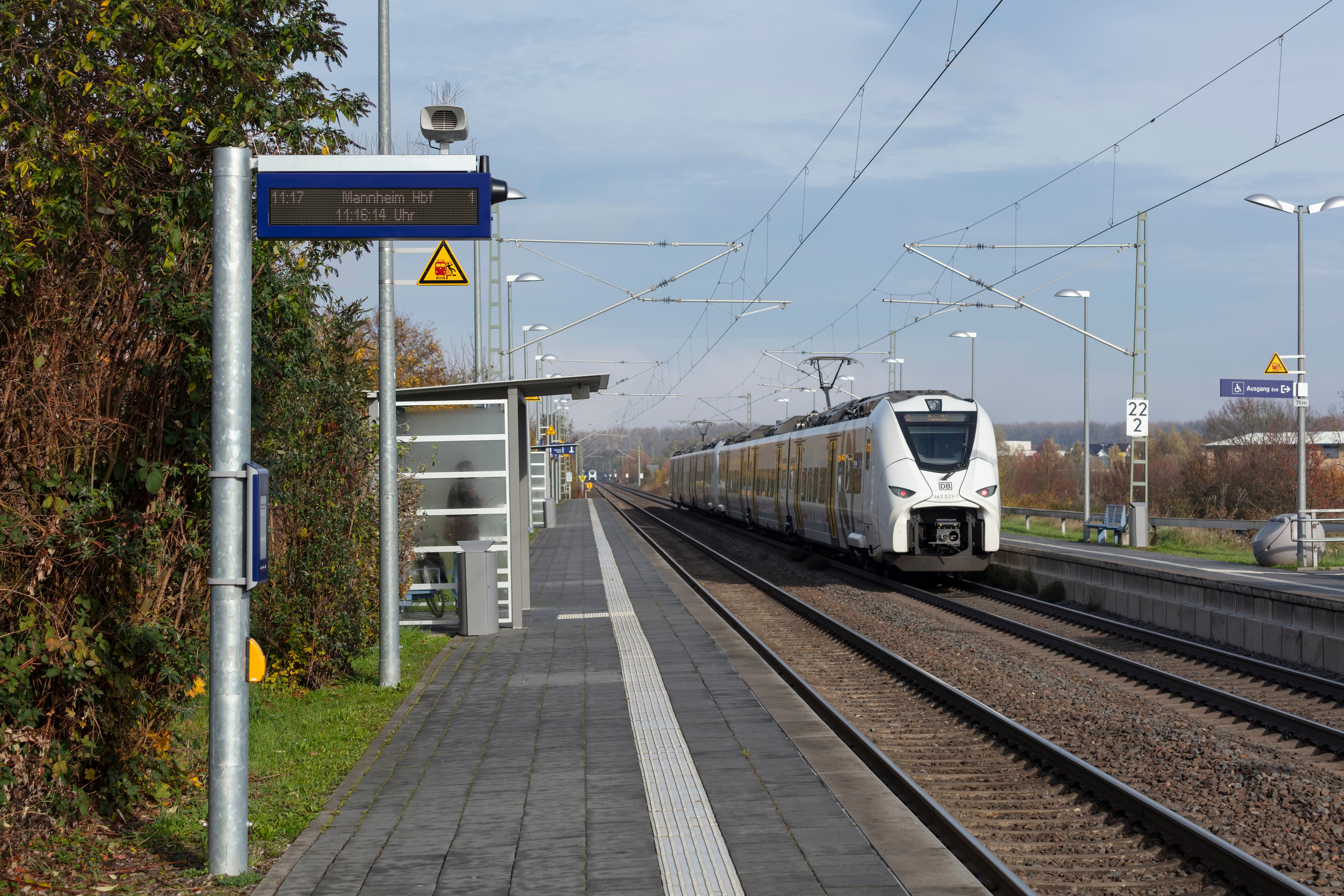 Links und rechts zwei Bahnsteige, in der Mitte zwei Gleise, einfahrender Zug.