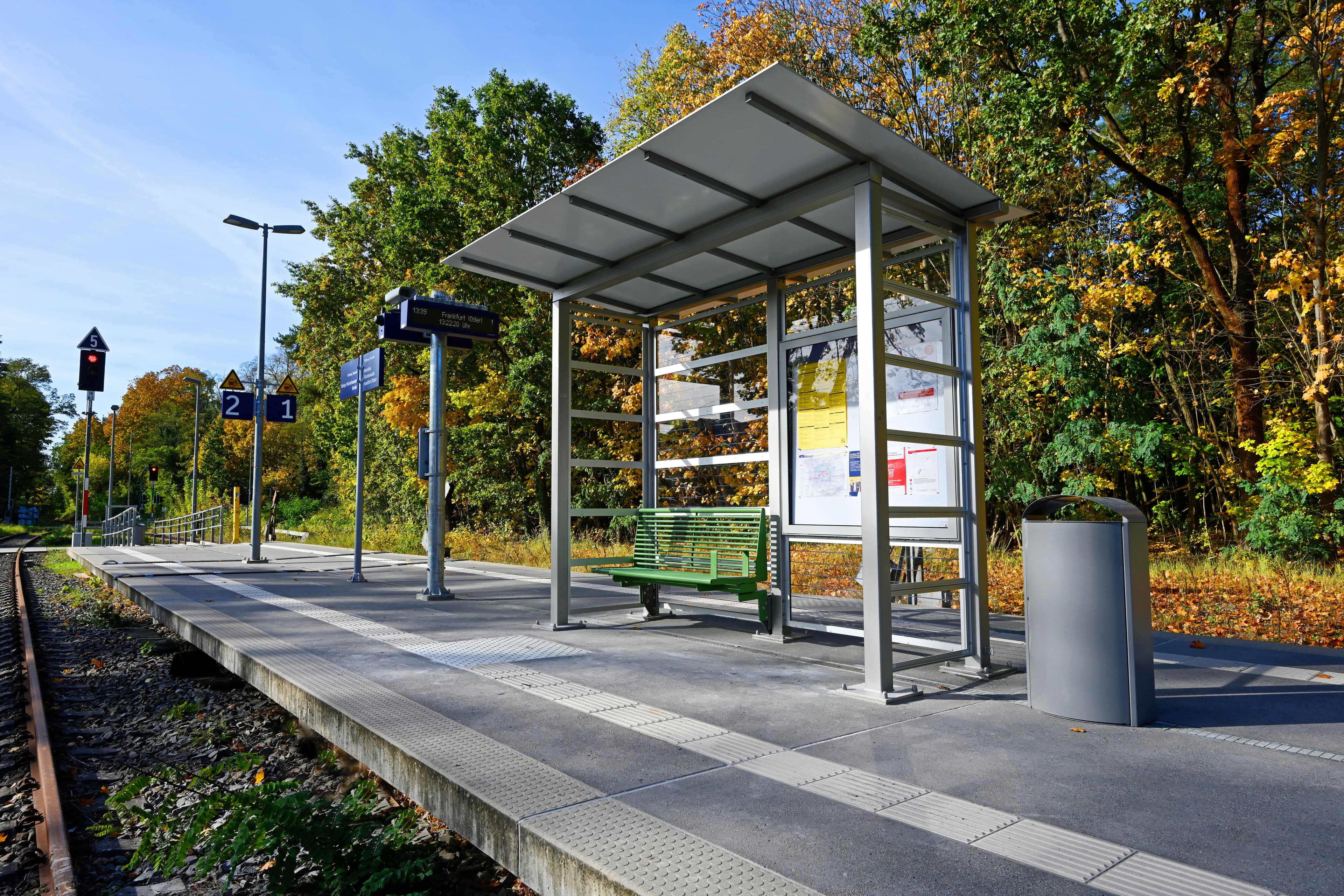 Blick auf ein Wetterschutzhaus mit Glaspaneelen mit grüner Sitzbank.