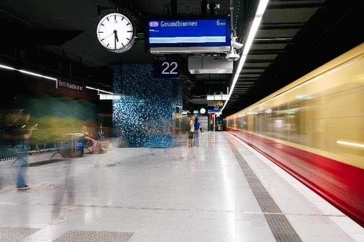 Bahnsteig der S15 mit einfahrendem Zug und gestalteten Wandflächen.