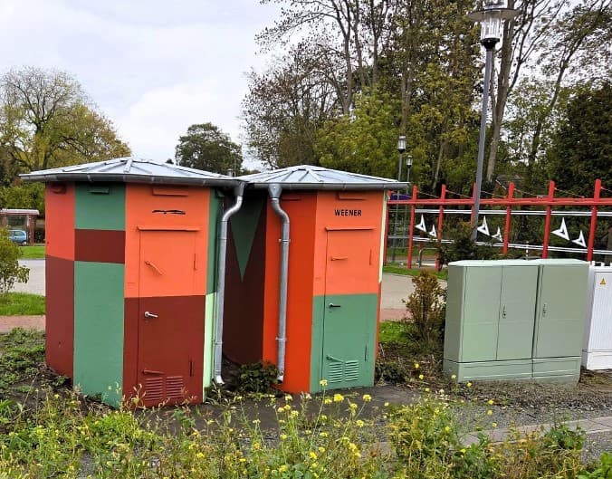 Zwei farblich gestaltete Schalthäuschen aus Beton.