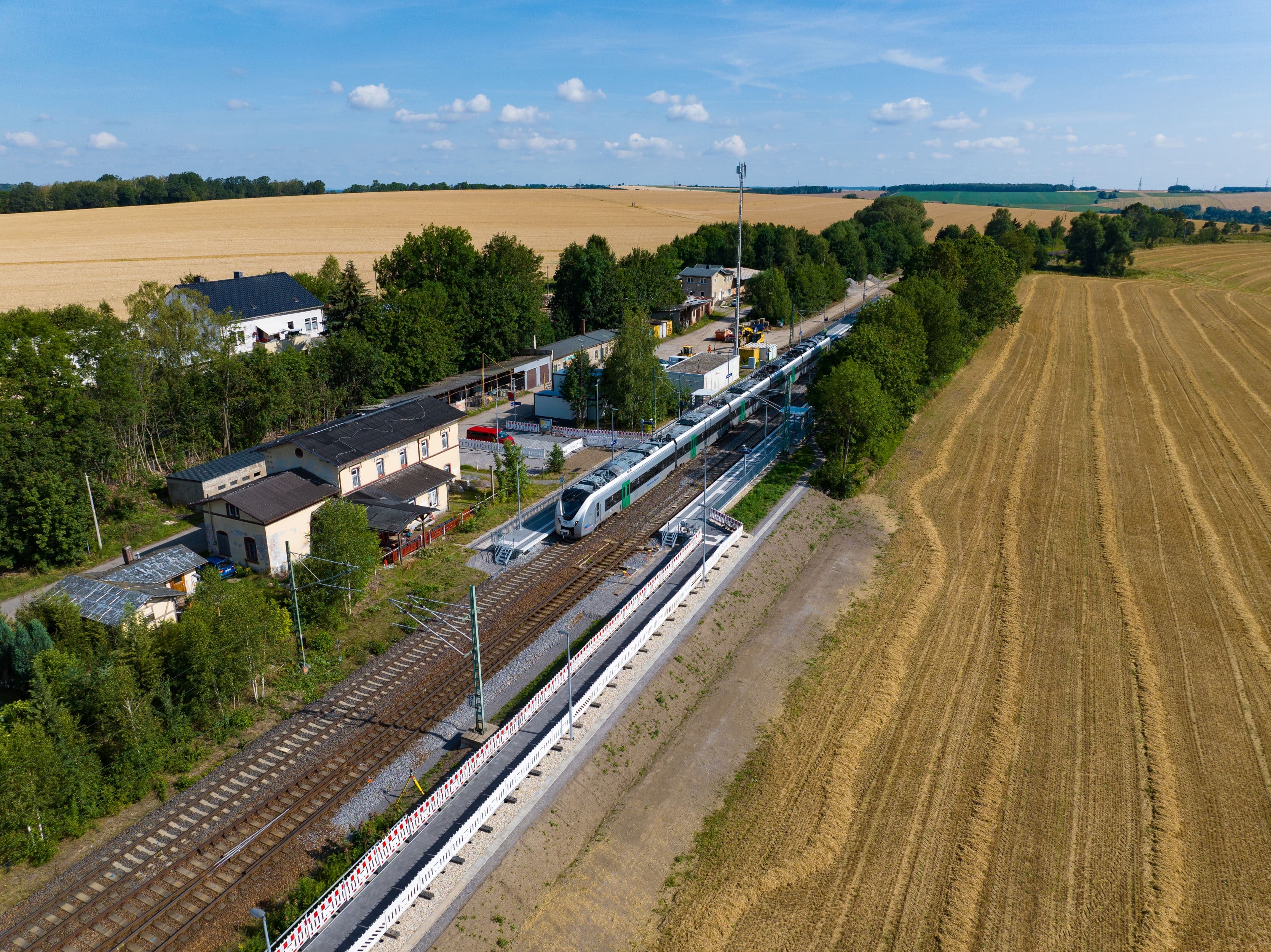 Zu sehen ist eine Luftbildaufnahme vom Bahnhof Frankenstein (Sachs) mit den beiden modernisierten Bahnsteigen und Feldern am Bildrand.