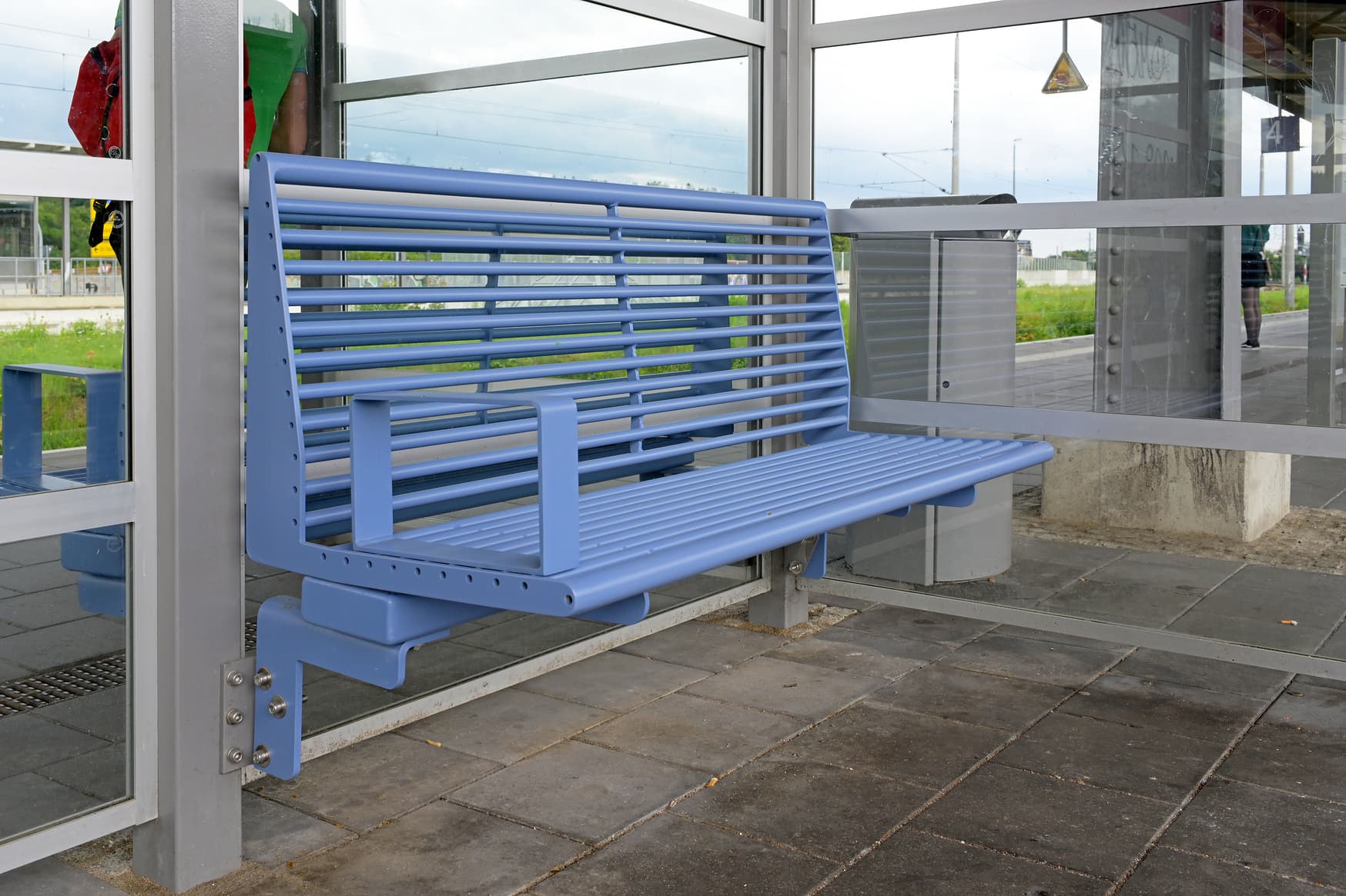 Zu sehen ist ein neue, blaue Sitzbank auf einem Bahnsteig.