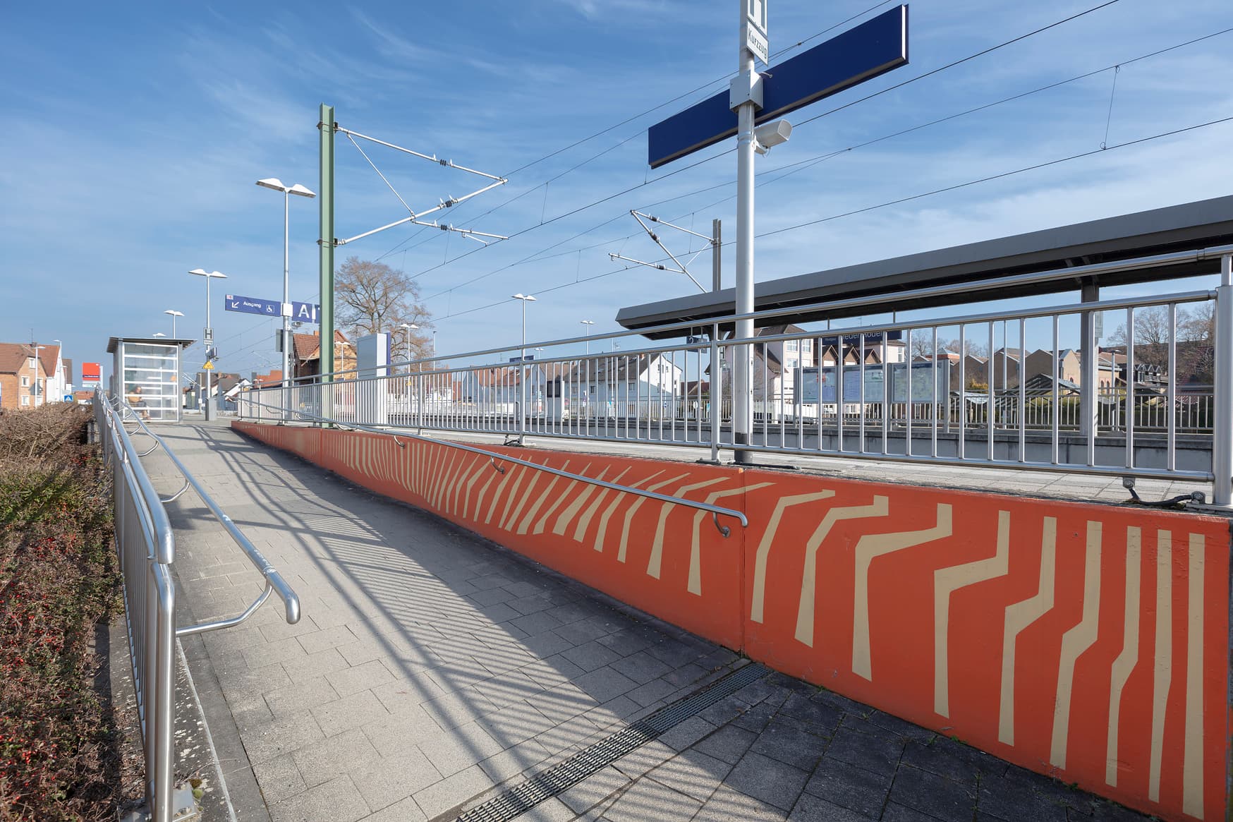 Eine rote Wand an der Zugangsrampe zum Bahnsteig mit den typischen Rastermuster.