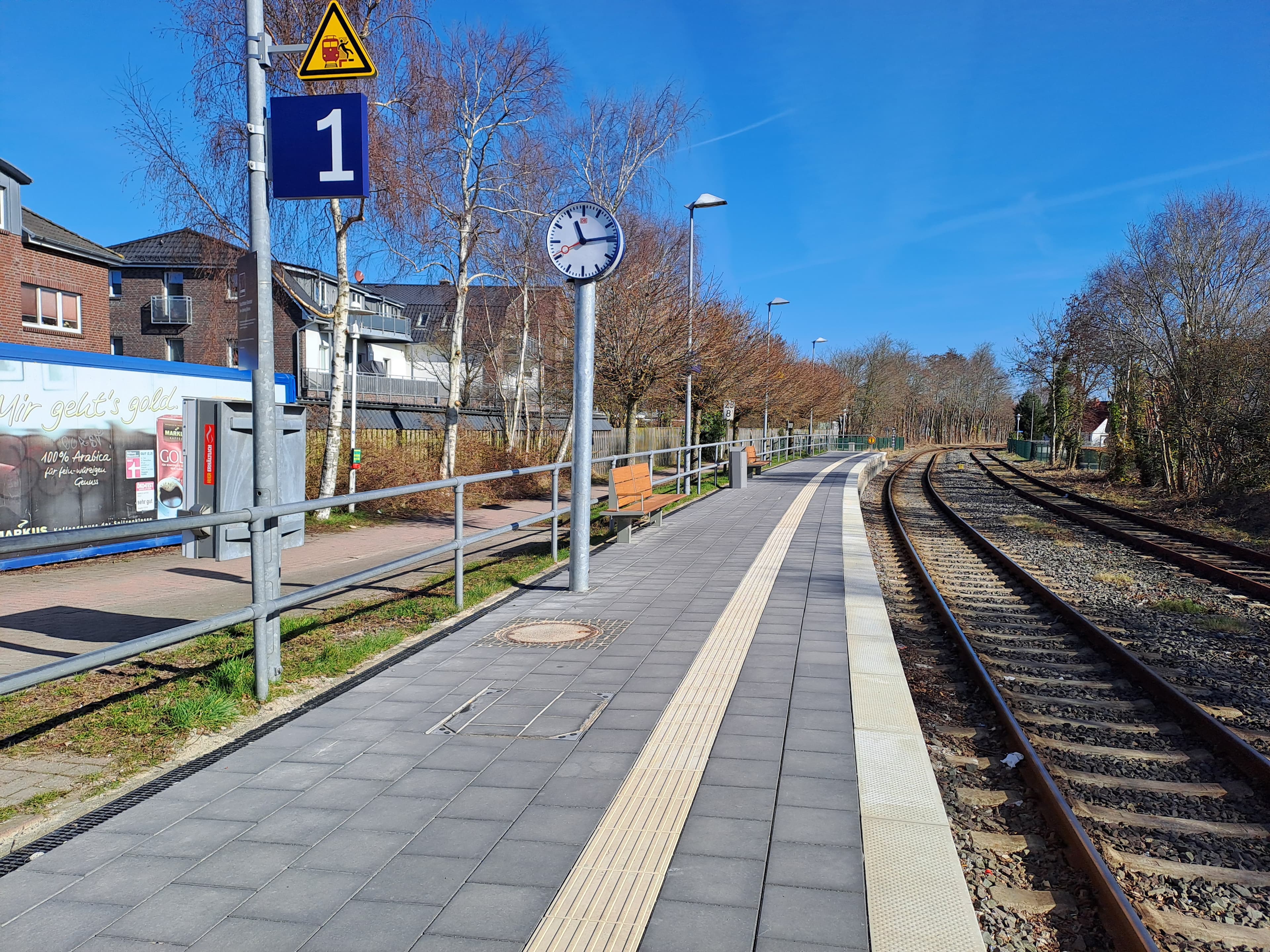 Im Bild der neu gepflasterte Bahnsteig mit Sitzbänken, Blindenleitstreifen und neuer Bahnhofsuhr