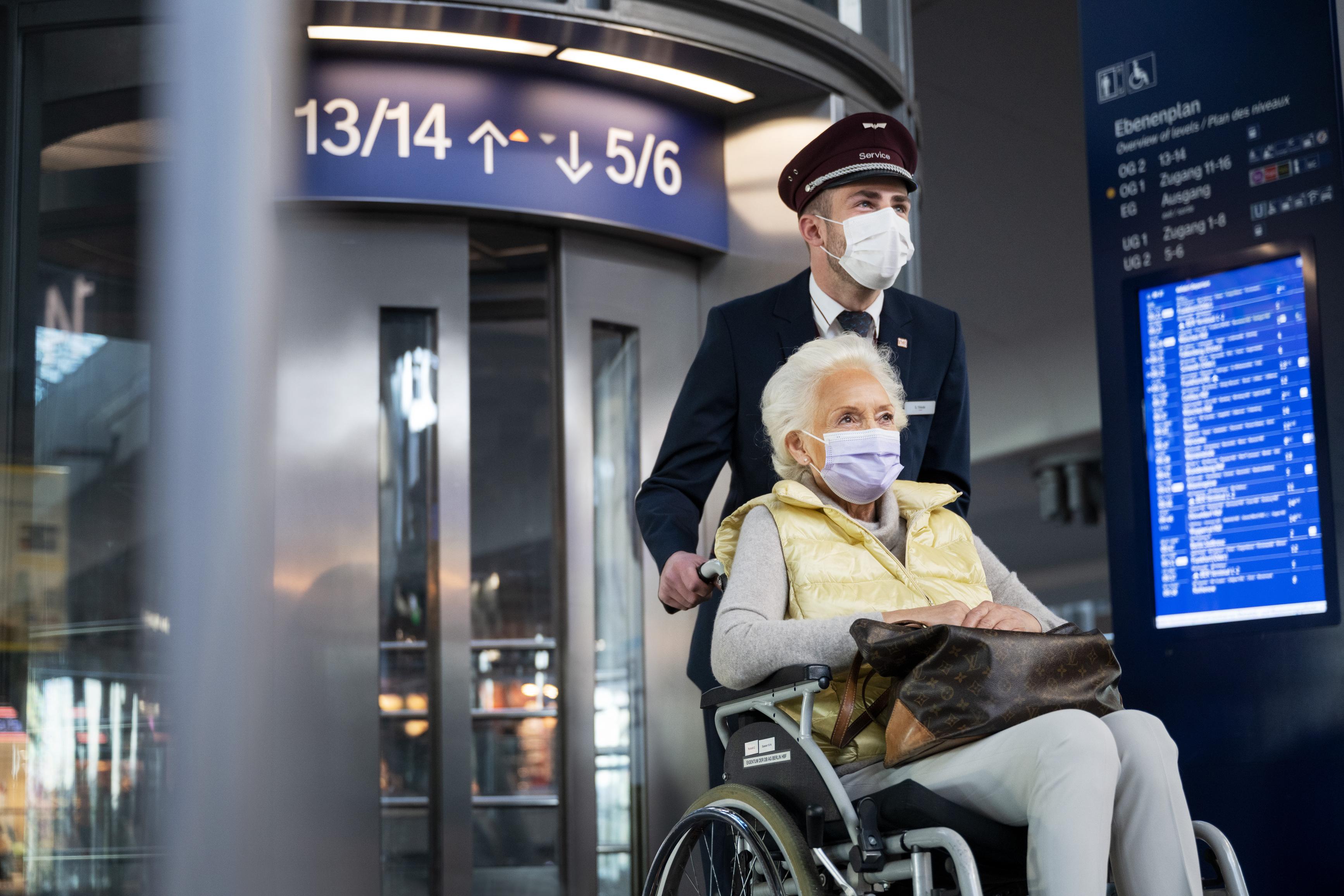 Ein DB Mitarbeiter hilft im Rahmen des Mobilitätsservices einer Rollstuhlfahrerin im Hauptbahnhof Berlin.