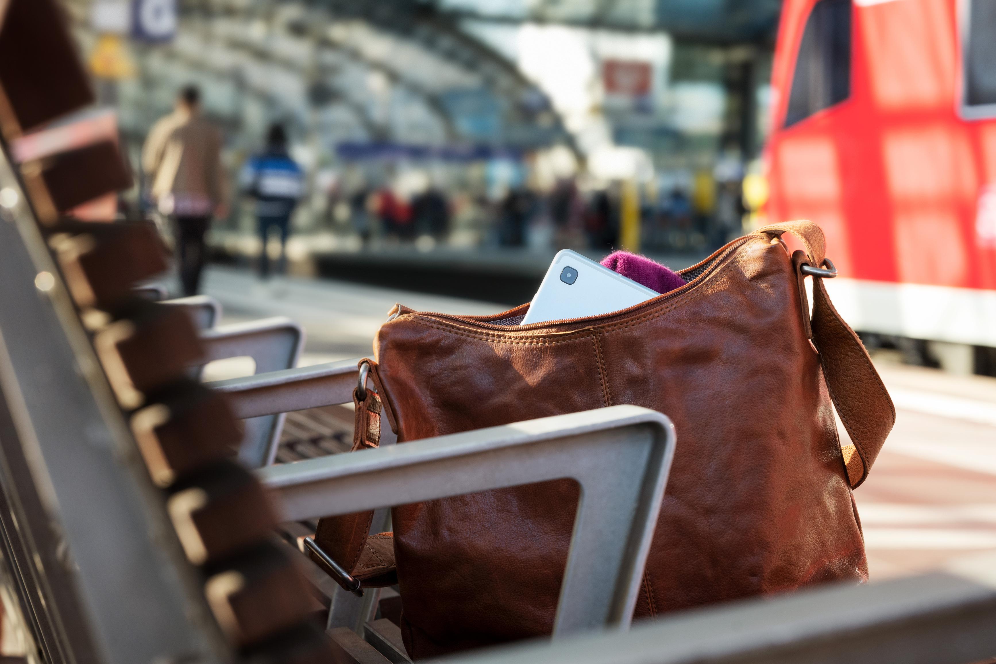 Eine verlorene Handtasche auf einer Bank an einem Bahnsteig.