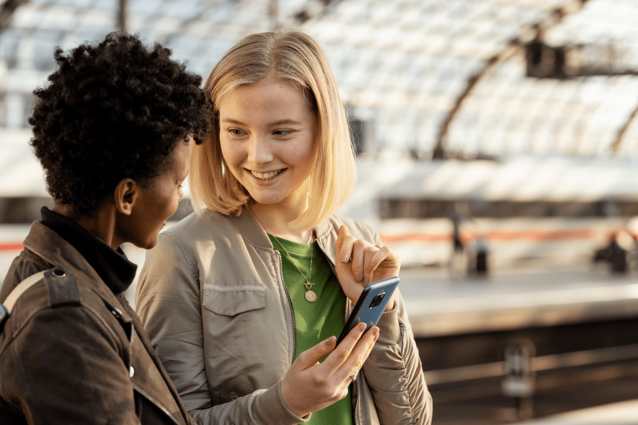 Kundinnen (junge Frauen) mit einem Handy auf dem Bahnsteig am Hauptbahnhof Berlin